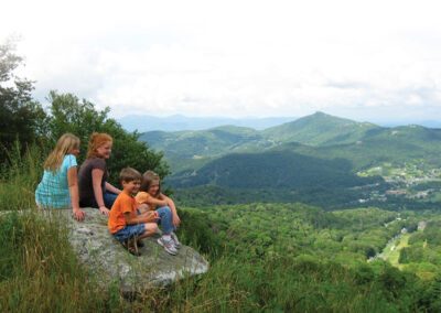 family sitting on rock enjoying the mountain views
